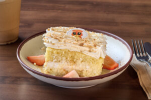 Catnip Tres Leches is a vanilla cake soaked with tres leches mix, whipped topping, cinnamon, strawberries, and a catnip crumble.